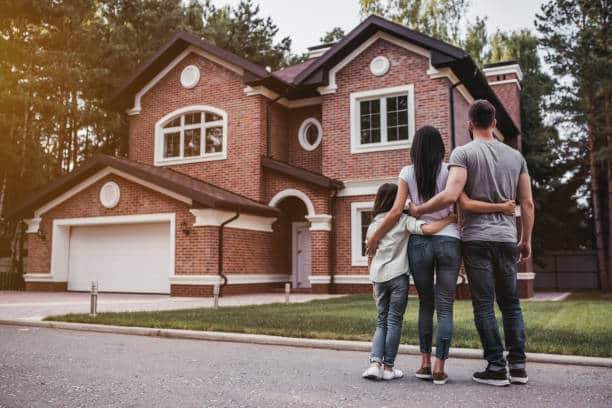 A family stands together admiring their beautiful home after a successful renovation.