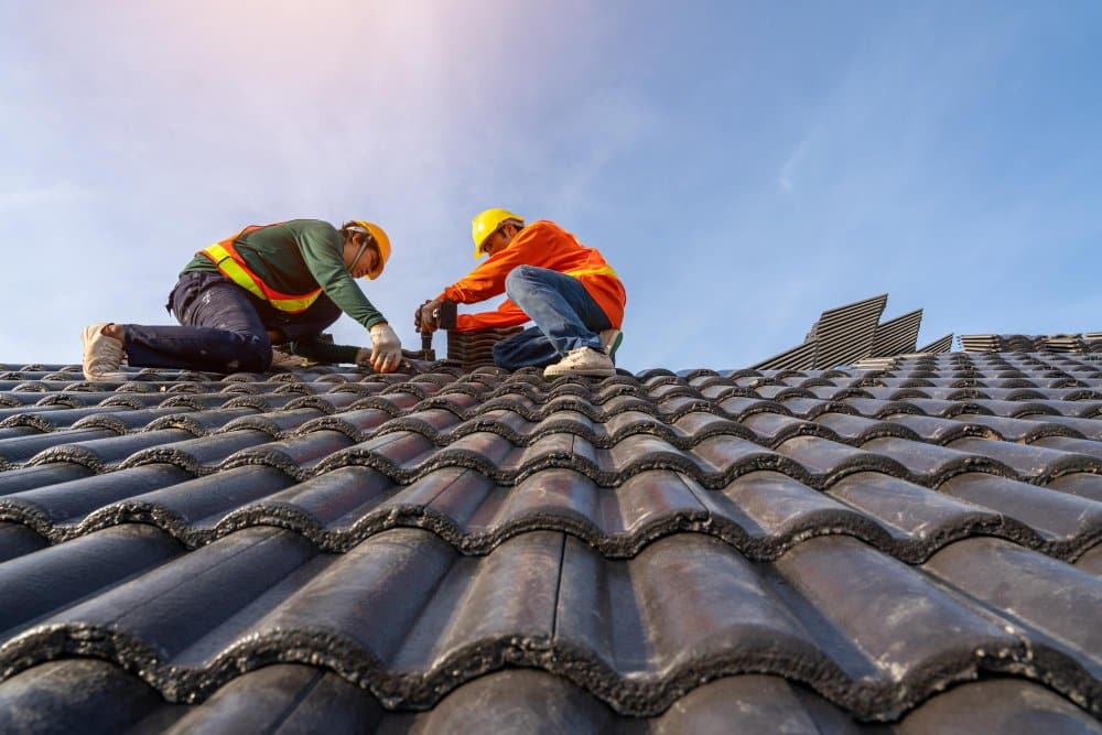 Two roof repair technicians fixing a client's roof.